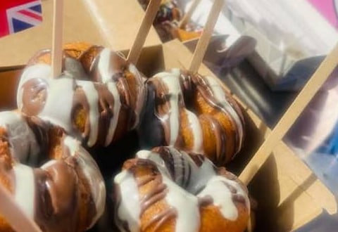 Close-up of hot mini donuts drizzled with milk and white chocolate