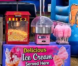 Pink candy floss next to a popcorn machine and ice cream banner